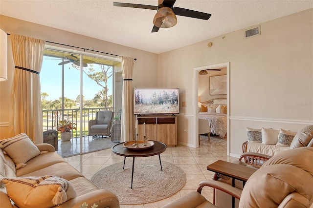 tiled living room with ceiling fan and a textured ceiling