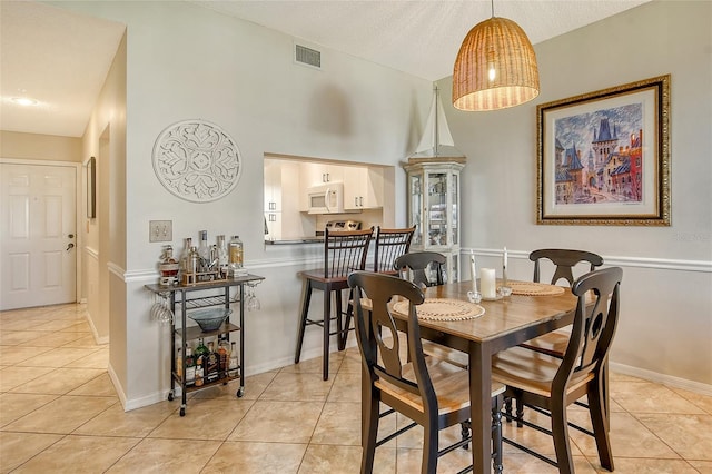 tiled dining area featuring a textured ceiling and lofted ceiling