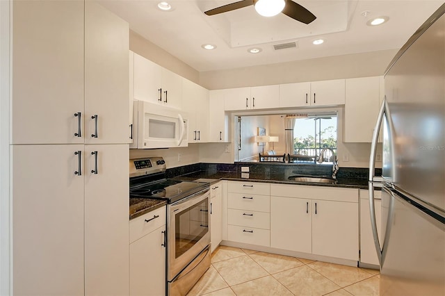 kitchen with appliances with stainless steel finishes, white cabinetry, dark stone counters, and sink