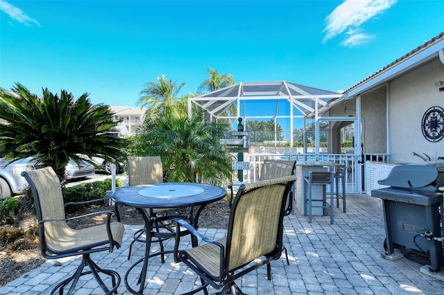 view of patio featuring glass enclosure, area for grilling, and a bar