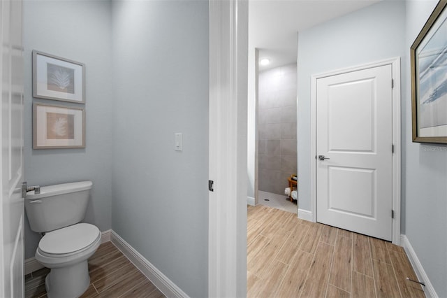 bathroom featuring tiled shower, toilet, and hardwood / wood-style flooring