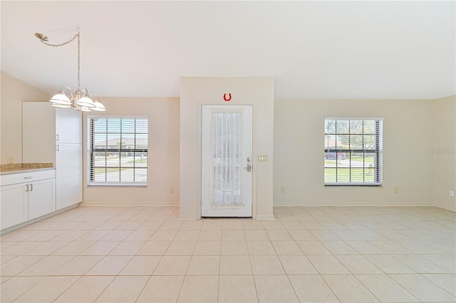 entryway featuring light tile patterned floors, a healthy amount of sunlight, and a notable chandelier