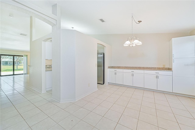 kitchen featuring white cabinets, stainless steel fridge, light tile patterned flooring, and hanging light fixtures