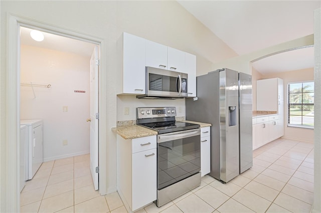 kitchen with independent washer and dryer, vaulted ceiling, stainless steel appliances, and white cabinetry