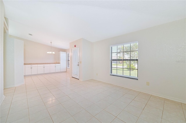 spare room with light tile patterned floors, a chandelier, and vaulted ceiling