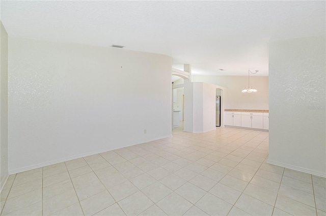 spare room featuring light tile patterned floors, vaulted ceiling, and an inviting chandelier