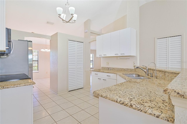 kitchen with sink, pendant lighting, a notable chandelier, white cabinets, and lofted ceiling