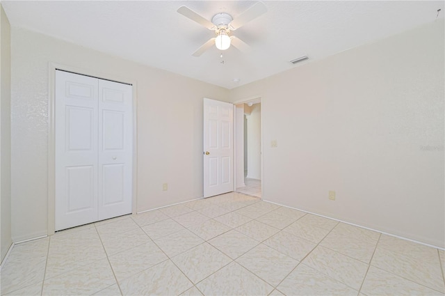 unfurnished bedroom with ceiling fan, light tile patterned flooring, and a closet