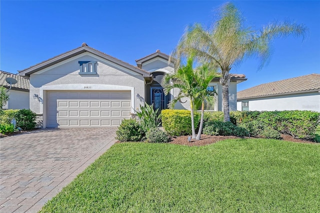 view of front of house featuring an attached garage, a front lawn, decorative driveway, and stucco siding