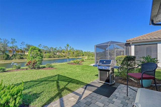 view of yard featuring a patio area, glass enclosure, and a water view