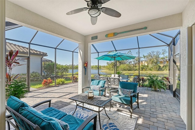 sunroom / solarium with ceiling fan and a water view