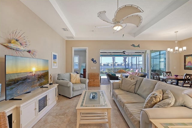 tiled living room with ceiling fan with notable chandelier and a raised ceiling