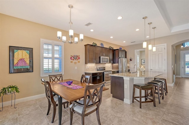 tiled dining space featuring sink and an inviting chandelier