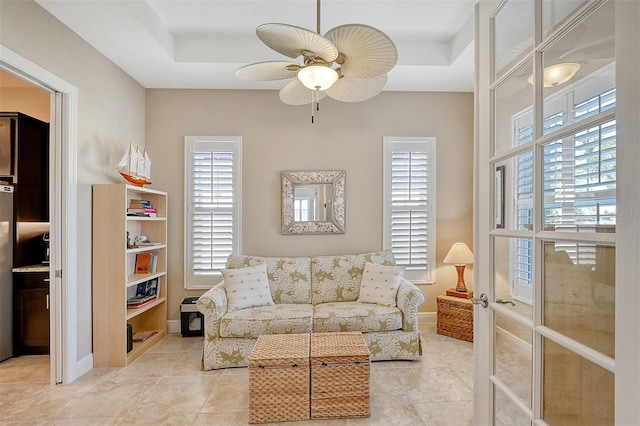 sitting room with a tray ceiling, ceiling fan, and light tile patterned flooring