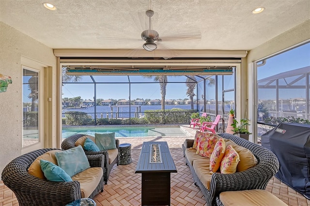 sunroom / solarium with ceiling fan and a water view