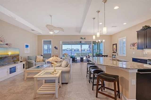 tiled living room with sink and ceiling fan with notable chandelier