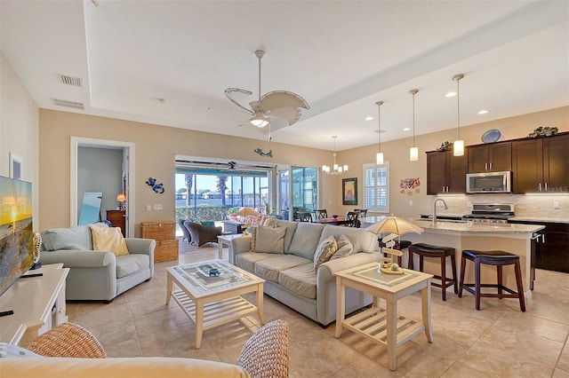 tiled living room with sink and ceiling fan with notable chandelier