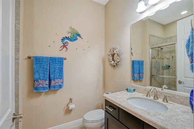 bathroom with a shower with door, vanity, and toilet