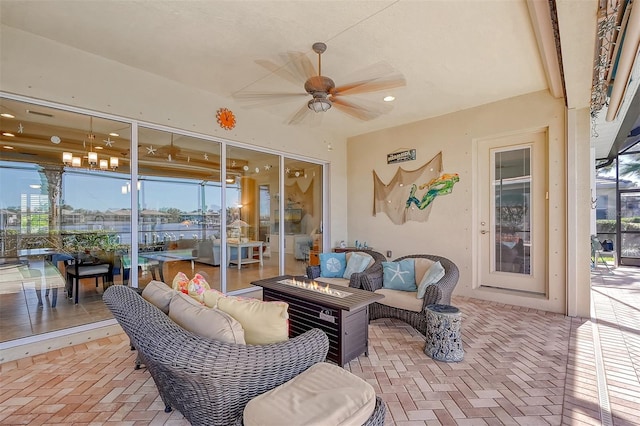 view of patio featuring ceiling fan and an outdoor living space with a fire pit