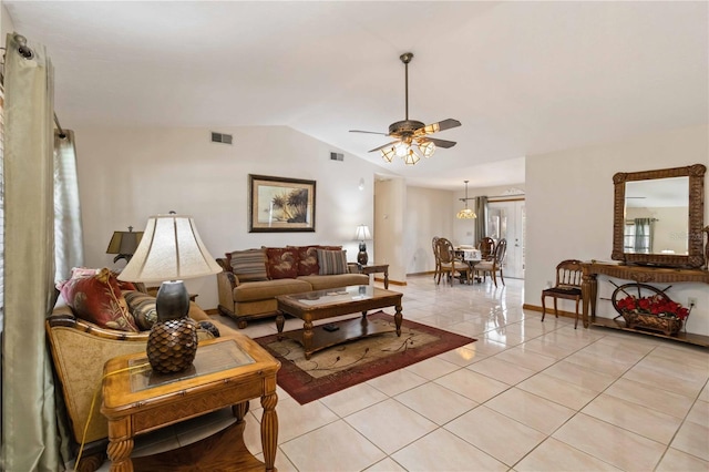 living room featuring ceiling fan with notable chandelier, light tile patterned flooring, and lofted ceiling