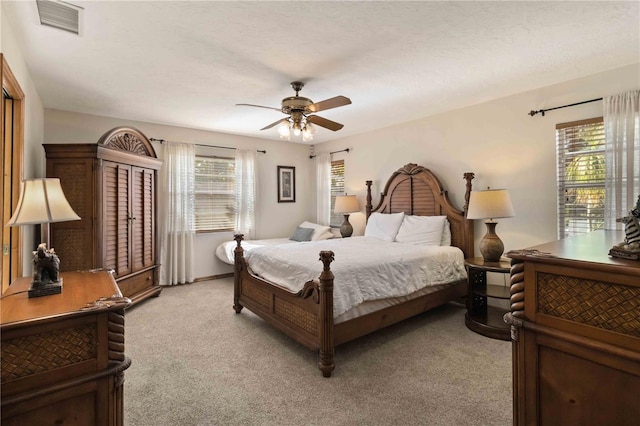 carpeted bedroom featuring ceiling fan and a textured ceiling