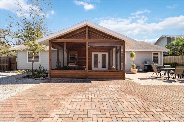 back of property with a sunroom, a patio area, and french doors