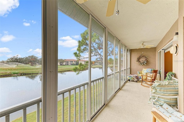 sunroom featuring ceiling fan and a water view