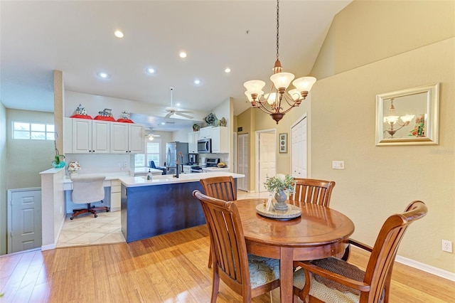 dining area with ceiling fan with notable chandelier, light hardwood / wood-style flooring, and lofted ceiling