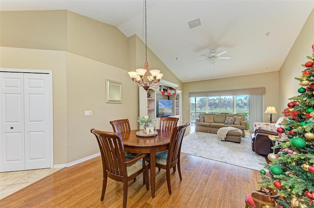 dining space featuring vaulted ceiling, ceiling fan with notable chandelier, and light wood-type flooring