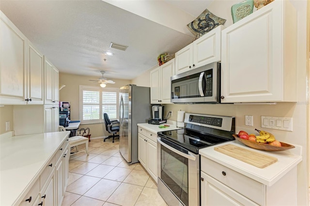 kitchen featuring ceiling fan, stainless steel appliances, light tile patterned floors, a textured ceiling, and white cabinets