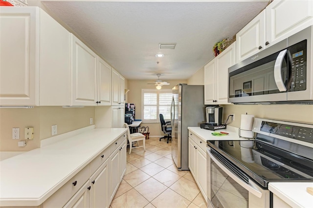 kitchen featuring light tile patterned floors, stainless steel appliances, white cabinetry, and ceiling fan