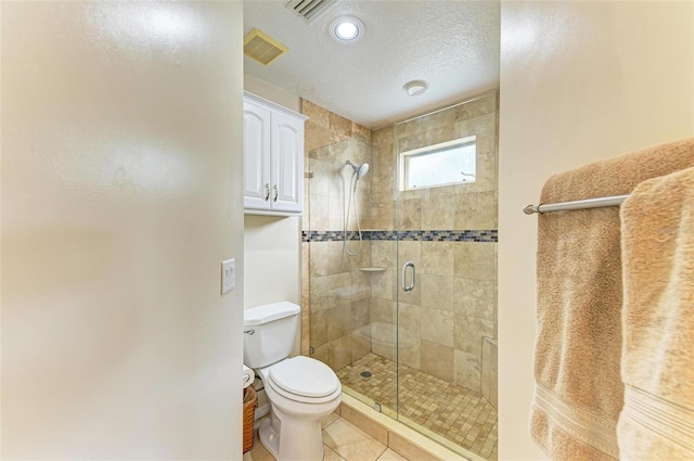 bathroom featuring a textured ceiling, tile patterned flooring, an enclosed shower, and toilet