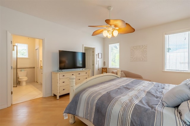 bedroom with ceiling fan, ensuite bathroom, and light wood-type flooring