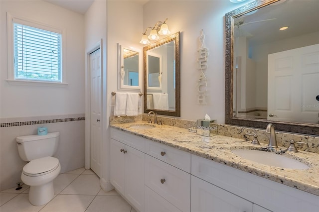 bathroom with tile patterned flooring, vanity, toilet, and tile walls