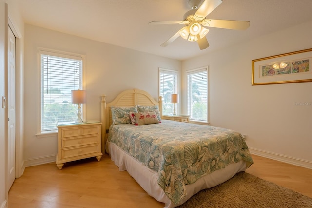 bedroom with light wood-type flooring, multiple windows, and ceiling fan