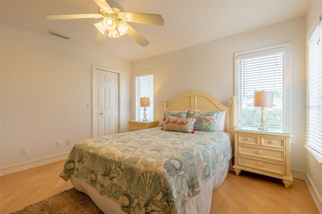 bedroom with multiple windows, ceiling fan, and a closet