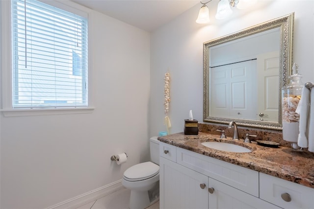 bathroom with tile patterned floors, vanity, a healthy amount of sunlight, and toilet