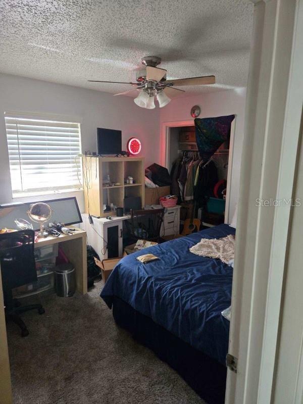 carpeted bedroom featuring a textured ceiling, a closet, and ceiling fan