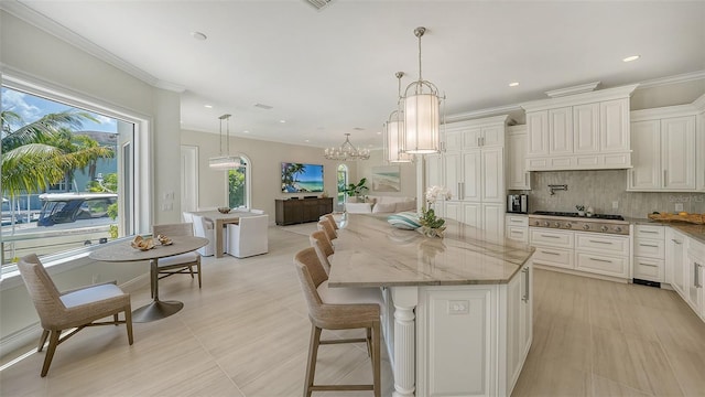 kitchen featuring backsplash, light stone counters, decorative light fixtures, a center island, and stainless steel gas stovetop