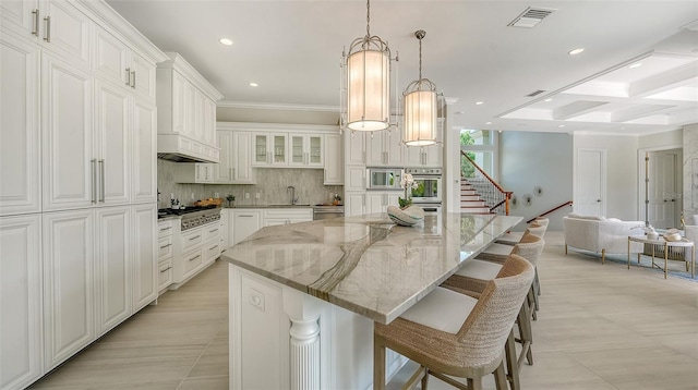 kitchen with light stone counters, a breakfast bar, stainless steel appliances, white cabinets, and a large island