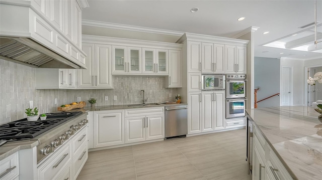 kitchen featuring custom exhaust hood, white cabinets, sink, light stone counters, and stainless steel appliances