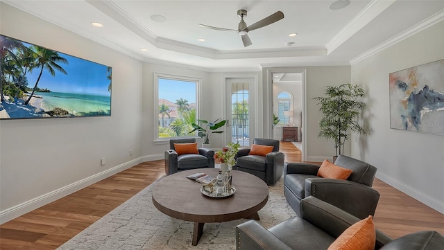 sitting room featuring ceiling fan, a raised ceiling, ornamental molding, and light hardwood / wood-style flooring