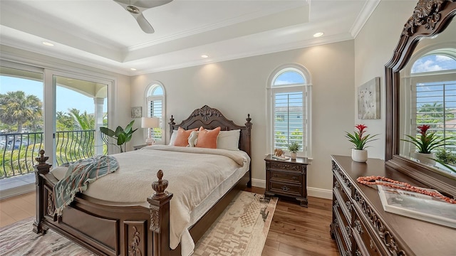 510 Bowsprit Ln, Longboat Key, FL 34228 - bedroom featuring a tray ceiling, multiple windows, access to outside, wood-type flooring, and crown molding