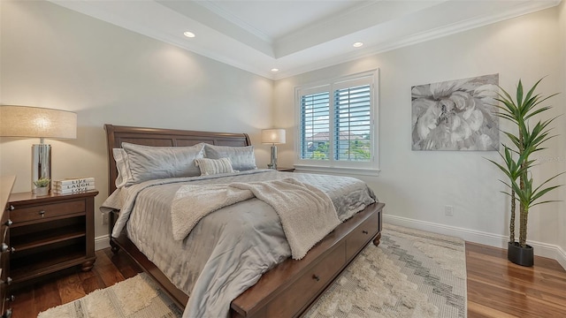 bedroom with hardwood / wood-style floors, a tray ceiling, and ornamental molding