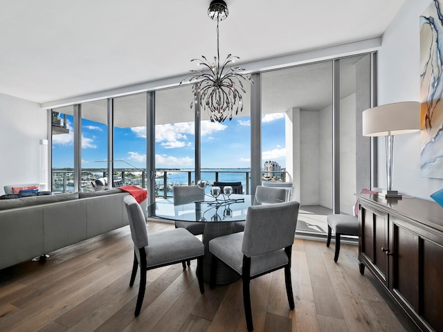 dining space featuring hardwood / wood-style floors, expansive windows, a water view, and a chandelier