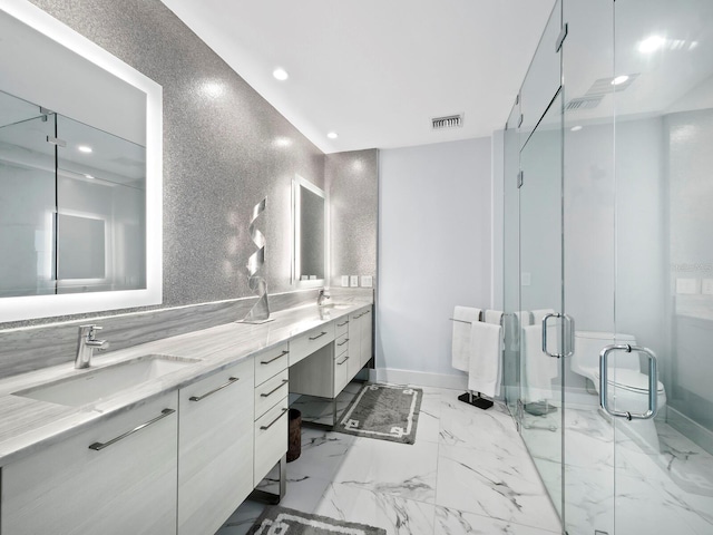 bathroom featuring vanity, toilet, and a shower with shower door