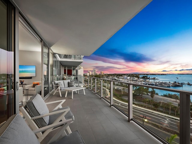 balcony at dusk featuring a water view