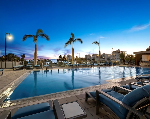 pool at dusk featuring a patio