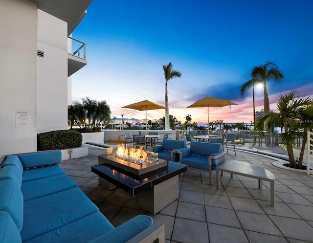 patio terrace at dusk with an outdoor living space with a fire pit