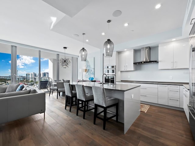 kitchen with wall chimney exhaust hood, dark hardwood / wood-style flooring, and white cabinetry